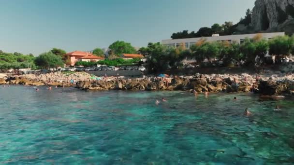 Palermo, Sycylia, Włochy-2019 sierpnia: Cinematic span nad skalistym kamiennym plaży. Przezroczysta, Kryształowa, turkusowa woda. Nierozpoznani ludzie pływają w morzu. W tle jest góra i — Wideo stockowe