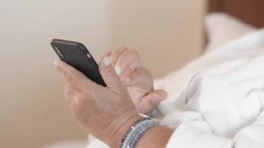 Beyaz cüppe içinde tanınmayan yetişkin kadın akıllı telefon kullanır, internet sitelerinde sörf. Yaş olgun insanlar tarafından teknoloji ve gadget'lar kullanma kavramı. Yavaş Çekim