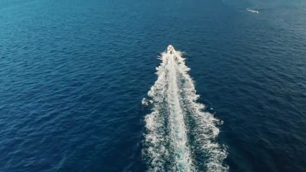 Fast Luxury Yacht rushes door de golven en verlaten een spoor van schuim op de turquoise Oceaan water. Een voorsprong op de Rocky Mountains. Het concept van het overwinnen van moeilijkheden. Luchtfoto van Drone. — Stockvideo