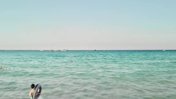 Неузнаваемая девушка-туристка входит в море с надувным кругом купания. Летние каникулы. На фоне яхты в открытом море. Воздушный беспилотник — стоковое видео