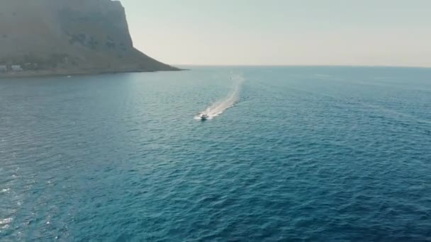 Palermo, Sicilië, Italië-augustus 2019: speedboot gaat snel naar de camera. Langs het turquoise water van de Oceaan op een achtergrond van Rocky Mountains. Zonsondergang tijd. Luchtfoto van Drone — Stockvideo