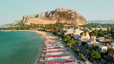 turkuaz su ile okyanus tarafından uzun plaj. Dağın arka planında ve bir sürü ağaçta. Gün batımı zamanı. Havadan insansız hava aracı vuruldu