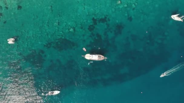 Concepto en el paraíso. Yates blancos en el agua turquesa transparente del océano. El agua brilla maravillosamente bajo el sol. Disparo aéreo con drones — Vídeo de stock