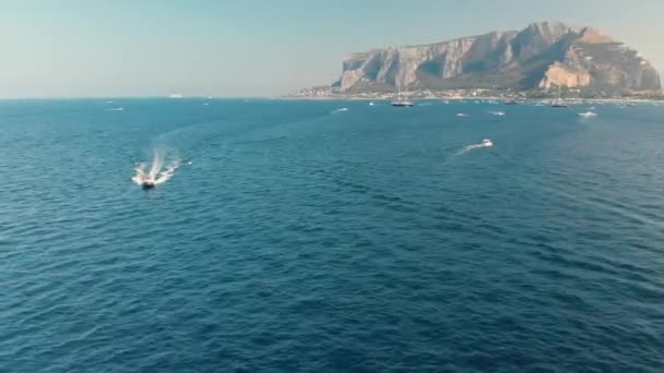 Motor de lujo barco rápidamente va en la superficie del agua del océano. Un panorama circular, montañas y una hermosa costa en el fondo. Disparo aéreo con drones . — Vídeo de stock