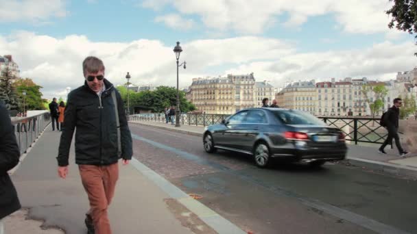 Париж, Франция - сентябрь 2019: типичная парижская улица. Местные и туристы ходят пешком. Проезжают велосипедисты и машины. На заднем плане типичные парижские дома — стоковое видео