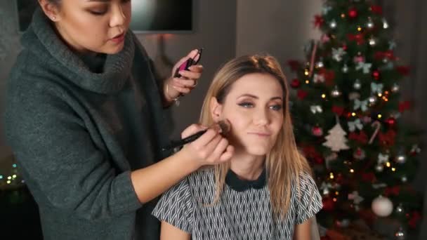 Asian make-up artist makes excuses to a dissatisfied customer. Apply blush with a big brush — Stock Video
