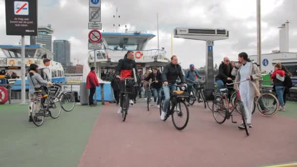 Amsterdam, Nizozemsko - říjen 2019: Lidé na kolech a chodci opouštějí trajekt přijíždějící na hlavní nádraží. — Stock video