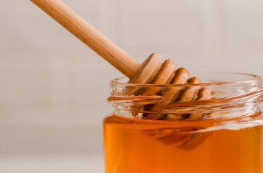 Tahta bal kaşığı, taze çiçek balı ile dolu cam bir kavanoza daldırılır..