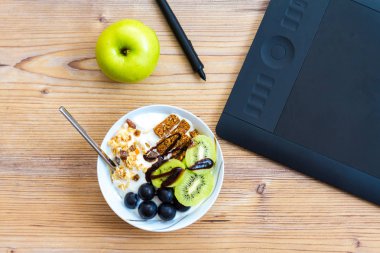 Grafik tasarım ve sağlıklı yaşam konsepti, üstten görünüm Kupası ile ham barlar ve üzüm, Kivi Meyve içinde. Ahşap masa arkasındaki tablet ve yeşil elma.