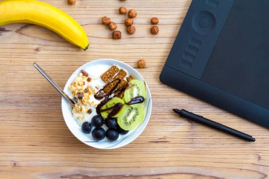 Grafik tasarım ve sağlıklı yaşam konsepti, üstten görünüm Kupası ile ham barlar ve üzüm, Kivi Meyve içinde. Ahşap masa arkasındaki tablet ve yeşil elma.