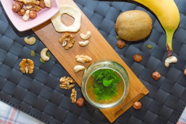 Sağlıklı snack yeme ve içme yeşil çay ve fındık, ham Bar, meyve, karışımı konseptiyle hizmet ahşap plaka üzerinde.