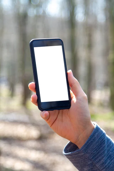 Mão segurando telefone com tela branca em branco ao ar livre — Fotografia de Stock