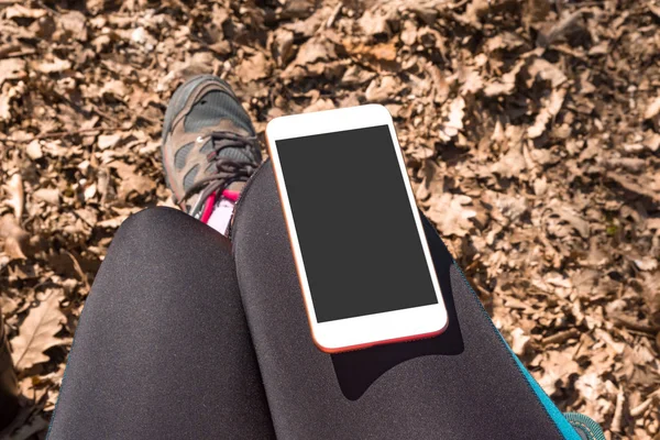 人が屋外に座っての膝の上の黒い画面で電話 — ストック写真