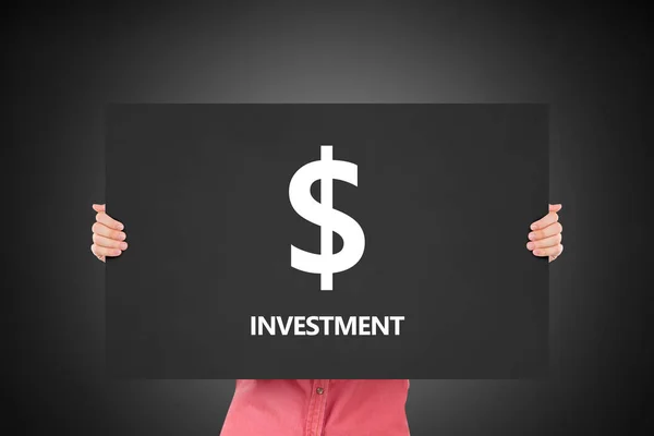 Hand holding dollar teken en investerings tekst op zwarte bord — Stockfoto