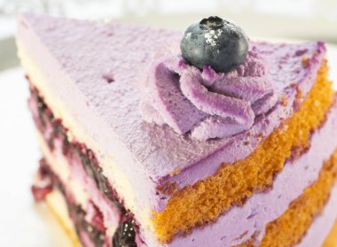 Beyaz arka planda bir tabakta üçgen şeklinde bir pasta.