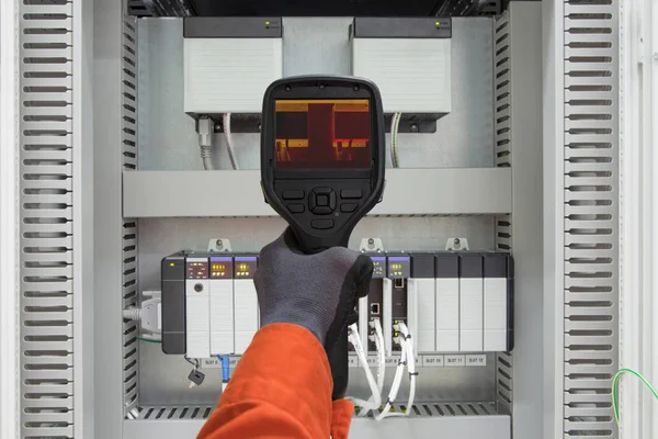 Electrician use thermo scan gun survey loosen cable, wiring and over load electric and instrument equipment to find an abnormal condition, electrical system site service job.