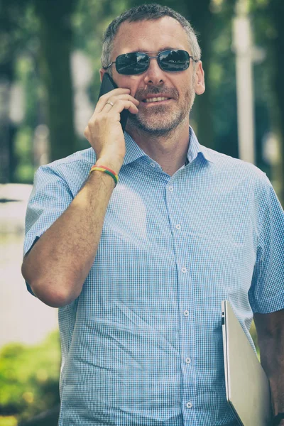 Podnikatel Drží Svůj Notebook Pomocí Svého Smartphonu Stojící Ulici — Stock fotografie