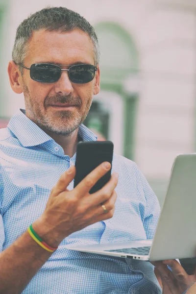 Businessman Holding His Laptop Using His Smartphone Street — Stock Photo, Image
