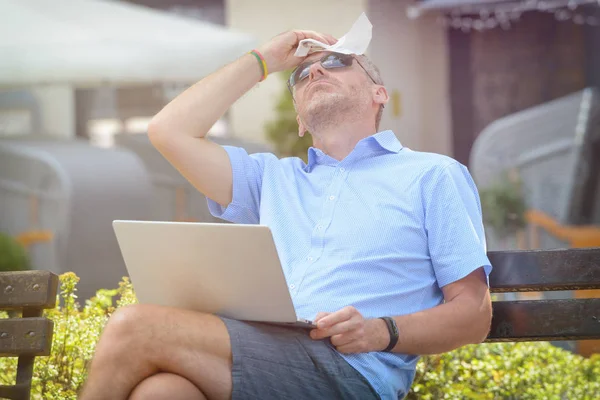 人在室外用笔记本电脑工作 用纸巾擦拭额头时 容易受热 — 图库照片