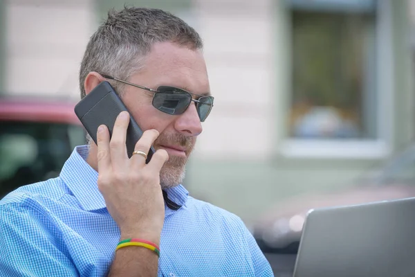 Businessman Holding His Laptop Using His Smartphone Sitting Bench City — Stock Photo, Image