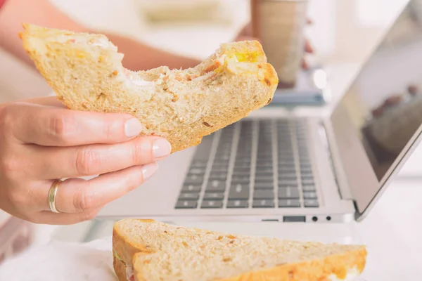 Γυναίκα Τρώει Ένα Σάντουιτς Πρωινό Και Πίνετε Καφέ Ενώ Λειτουργεί — Φωτογραφία Αρχείου