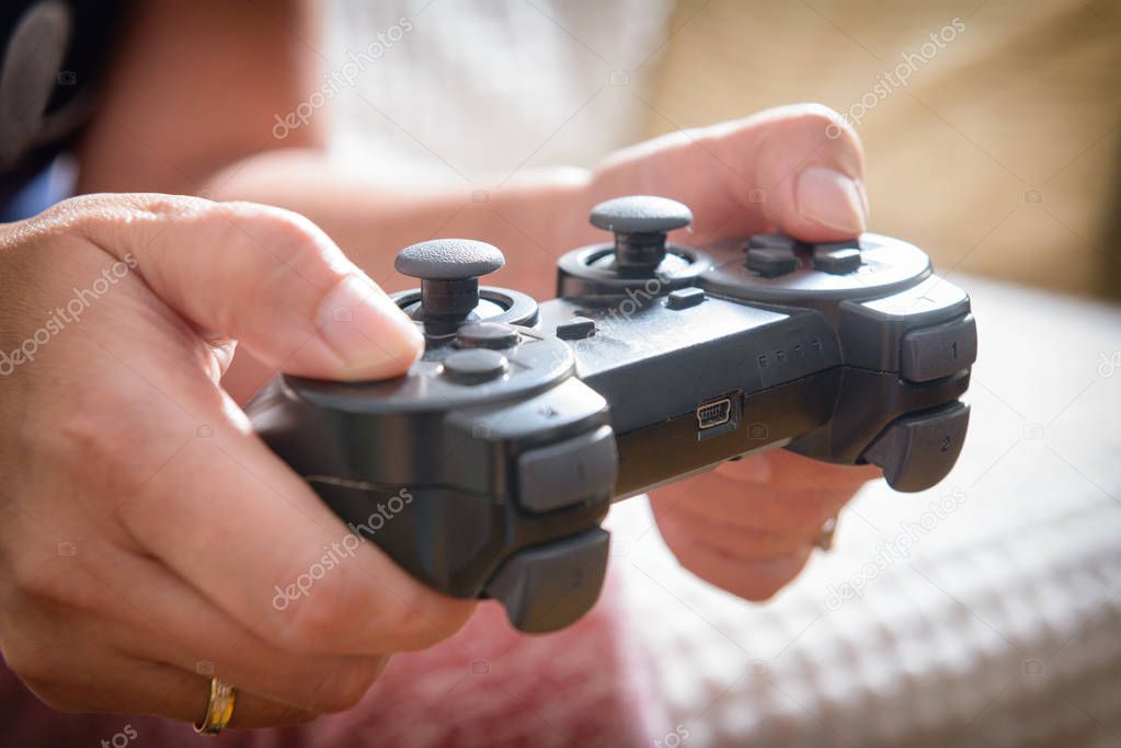 Mature woman or wife plays video game using the gamepad at home