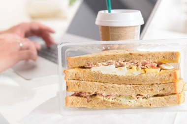 Kahvaltı sandviç yeme ve içme kahve ile bir dizüstü bilgisayar çalışırken kadın