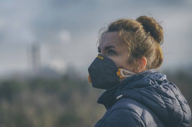 Gerçek bir anti-kirlilik, anti-duman ve virüsler takan kadın yüz maskesi; havada yoğun duman.