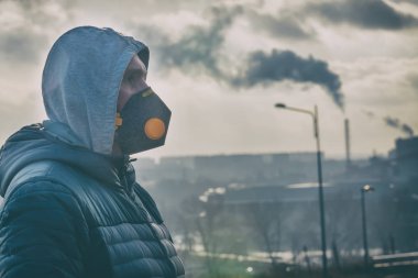 Gerçek bir anti-kirlilik, anti-kirli hava ve virüsler takan adam yüz maskesi; havada yoğun duman.