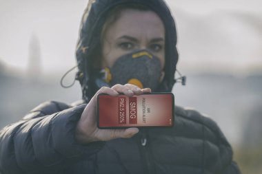 Gerçek anti-çevre kirliliği, Anti-smog giyen kadın ve virüs yüz maskesi ve akıllı telefon uygulaması ile Şu anki hava kirliliği kontrol