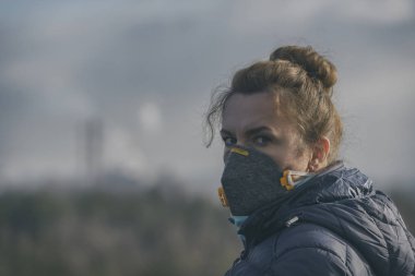 Gerçek bir anti-kirlilik, anti-duman ve virüsler takan kadın yüz maskesi; havada yoğun duman.