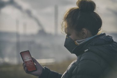 Woman wearing a real anti-pollution, anti-smog and viruses face mask and checking current air pollution with smart phone app clipart