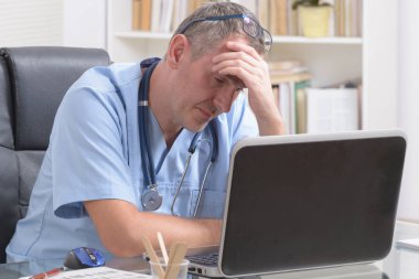 Çok çalışan doktor ofisinde oturuyor. 