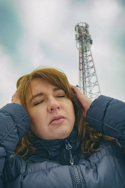 女性は携帯電話ネットワークの送信機のコンセプトから Bts 有害な放射線に近い彼女の頭を保持しています — ストック写真