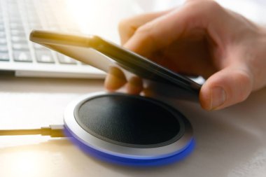 Smartphone kablosuz şarj yakınındaki elinde yastık, şarj cihazı.