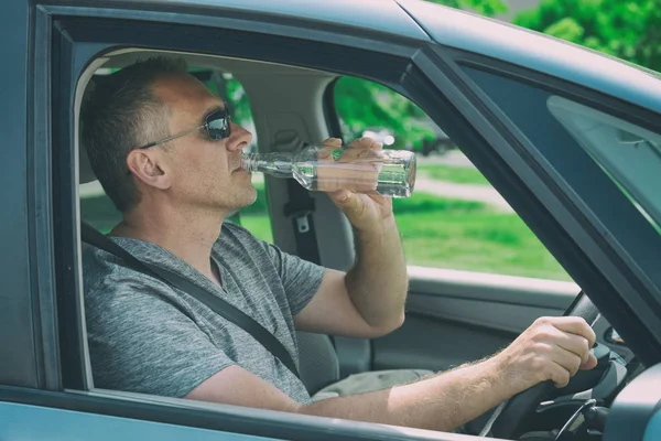 Mężczyzna pijący alkohol podczas jazdy samochodem — Zdjęcie stockowe