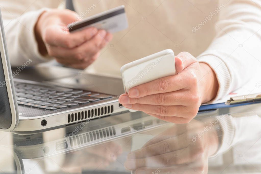Womans hand holding credit card and smartphone