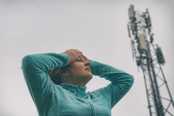 Женщина держит голову возле 5G BTS — стоковое фото