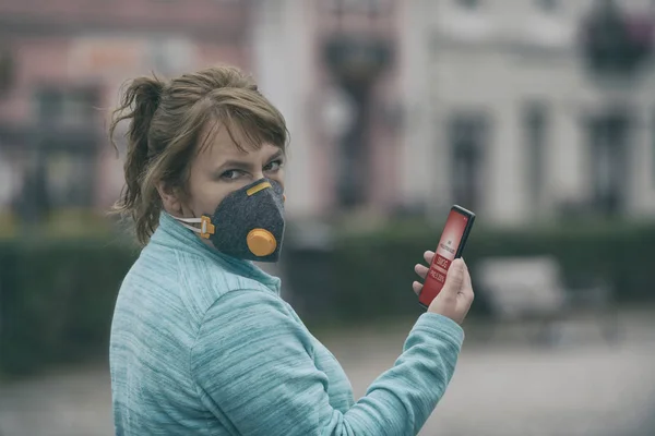 Woman wearing a real anti-smog face mask and checking current ai — Stock Photo, Image