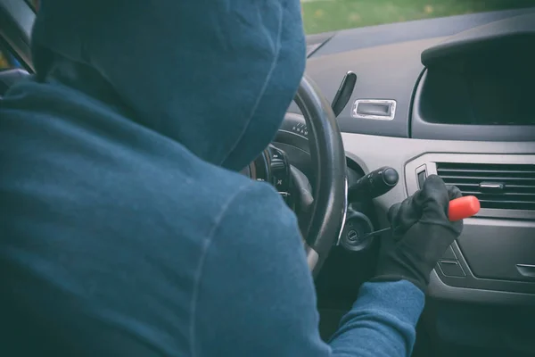 Hooded thief sits in the car and tries to break the ignition swi — Zdjęcie stockowe