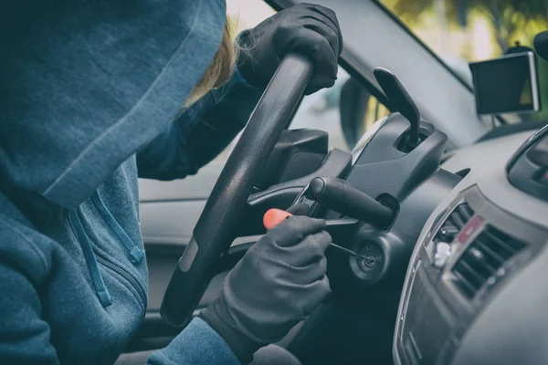 Hooded thief sits in the car and tries to break the ignition swi — Stock Photo, Image