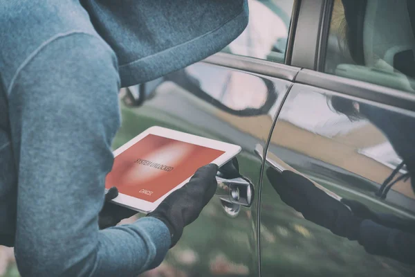 Ladrón encapuchado intenta romper los sistemas de seguridad del coche con tabl —  Fotos de Stock