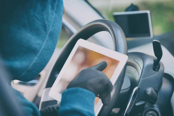 Hooded thief tries to break the car's security systems with tabl — Stock Photo, Image