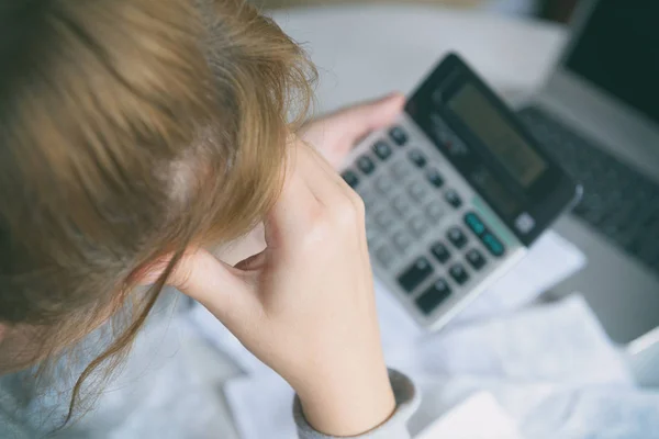 Vrouw gebruikt een rekenmachine om de kosten thuis op te sommen — Stockfoto
