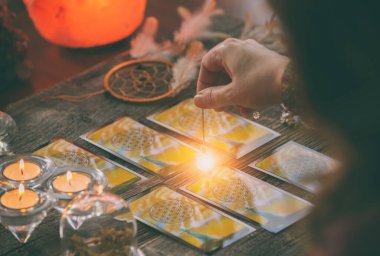Falcı tarot kartlarının üzerinde sarkacı tutuyor.