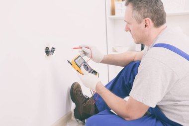 Elektrik soket voltajını dijital çokölçer ile kontrol ediyor
