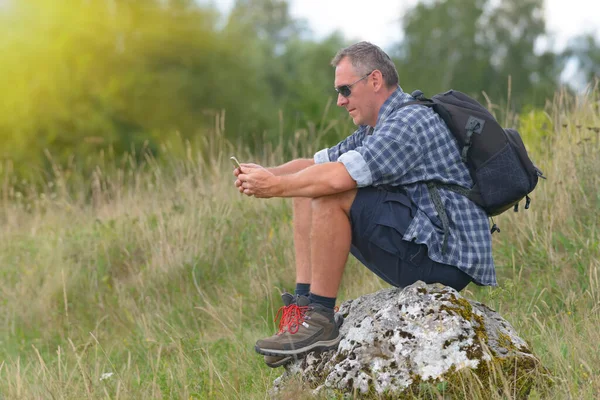 Człowiek Backpacker Siedzi Skale Smartfonem — Zdjęcie stockowe