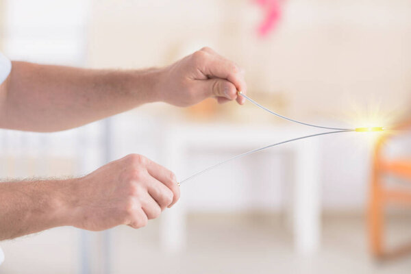 Man dowsing wirh dividing rod to locate ground water under surface or currents of earth radiation to check home for safe zones.