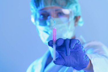 Laboratuvarda çalışan bilim adamı elinde yeni bir anti-viral ilaçla bir şırınga tutuyor.