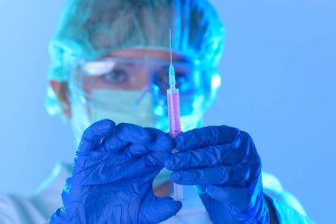 Laboratuvarda çalışan bilim adamı elinde yeni bir anti-viral ilaçla bir şırınga tutuyor.